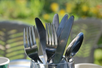 Metal cutlery in a glass. Stainless steel spoons, forks and knives stand in a glass transparent...