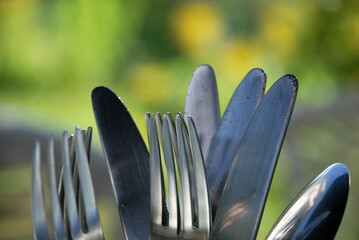 Metal cutlery in a glass. Stainless steel spoons, forks and knives stand in a glass transparent...