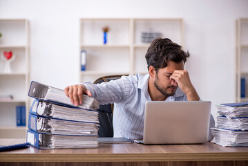 Young male employee unhappy with excessive work in the office