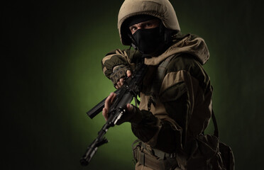 a Russian soldier in a helmet in military clothes with a Kalashnikov assault rifle on a dark...