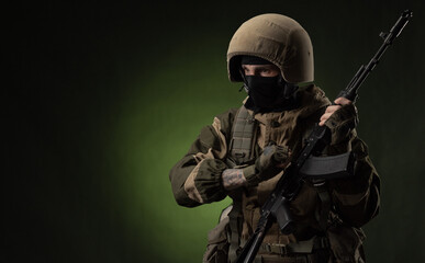 a Russian soldier in a helmet in military clothes with a Kalashnikov assault rifle on a dark...