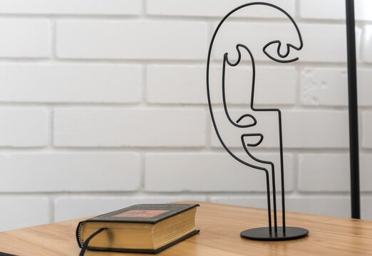 coffee table with a book and an abstract figure of the head against the background of a white brick wall
