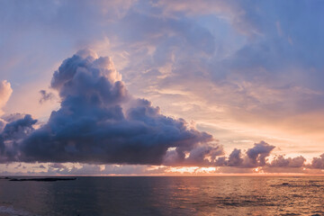 a large lilac dark cloud cloud over a quiet calm sea, a beautiful evening sunset in the tropics