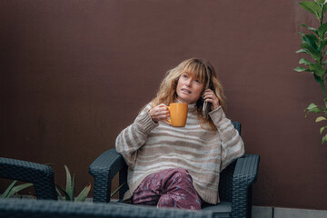 middle-aged adult woman with mobile phone on terrace at home
