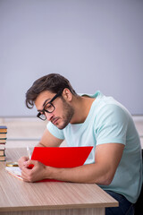 Obraz premium Young male student preparing for exams in the classroom