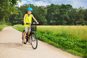 Obraz premium Young boy sit and ride bicycle in the park near field