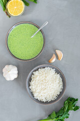 Green Indian chutney sauce. With fresh mint pudina and yogurt. Spicy indian cuisine. Served with rice, lemon, garlic and parsley on grey background. Healthy fresh dip for snacks