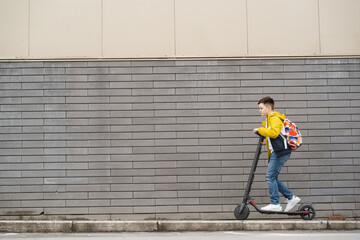 Handsome teenager riding an electric scooter