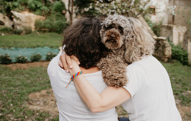 Backwards lesbian couple with poodle pet dog outdoors at sunset