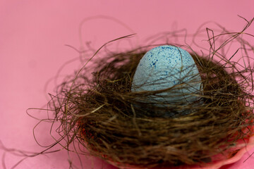 The egg lies in the nest on a pink background. A copy of the space. Easter and spring mood