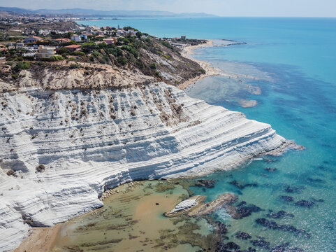 Aerial view of white rocky cliffs at Scala dei Turchi, Sicily, Italy, with turquoise clear water. Drone shot of the limestone rock formation and beach
