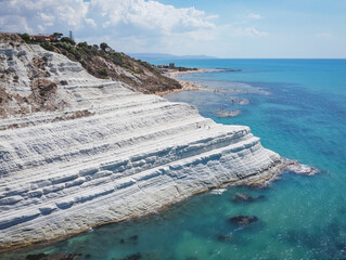 Aerial view of white rocky cliffs at Scala dei Turchi, Sicily, Italy, with turquoise clear water. Drone shot of the limestone rock formation and beach