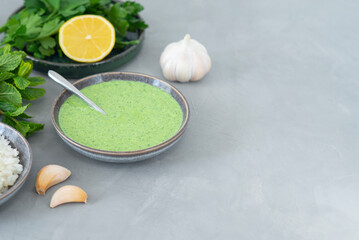 Serving healthy fresh green chutney sauce. With fresh mint pudina and yogurt. Spicy indian cuisine. With rice, lemon, garlic and parsley. Grey background, copy space