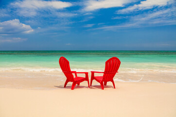 Tropical island with red chairs on sandy beach