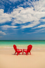 Fototapeta na wymiar Turquoise ocean with red chairs on sandy beach