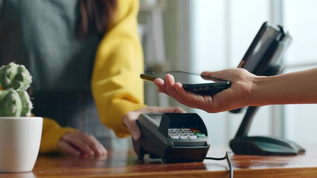 Customer using phone for payment at cafe restaurant, cashless technology and money transfer concept