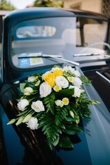 Wedding bouquet on the hood of a dark elegant vintage car 