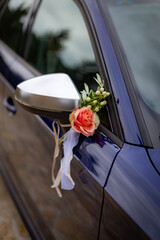 Wedding bouquet tied to the side mirror of a dark elegant car