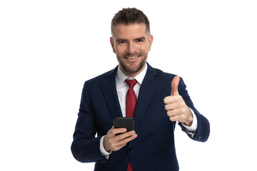 businessman giving a thumbs up, holding a mobile phone