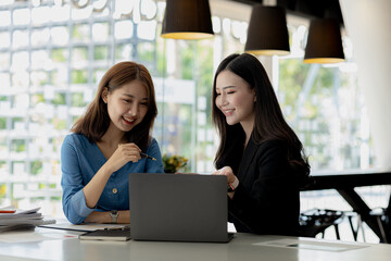 Atmosphere in the office of a startup company, two female employees are discussing, brainstorming ideas to working on summaries and marketing plans to increase sales and prepare reports to managers.