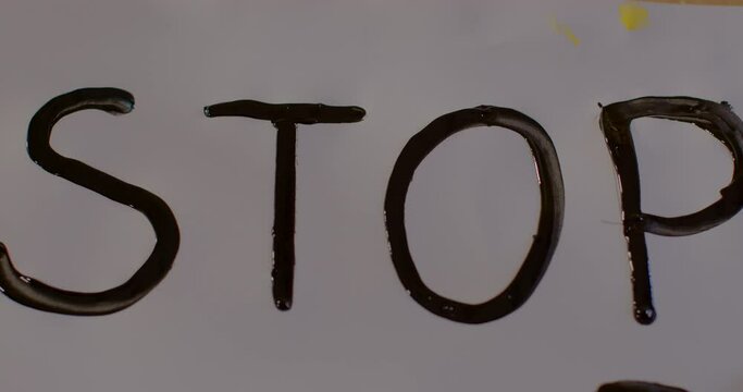 Stop word is stenciled with black paint on white paper surface. Expression of protest, objection, disapproval or dissent towards an idea or action.