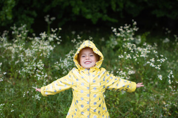 Little girl smiles when it rains. Spring walk in nature