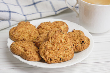 Close-up of freshly baked homemade cookies with additives. Shortbread cookies in the shape of a heart on a white saucer. Homemade cakes for breakfast and coffee in a white porcelain cup.