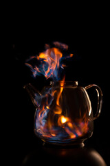 Fire within a see through glass tea pot showing beautiful orange and blue flames inferno giving the idea of substance or alcohol abuse.