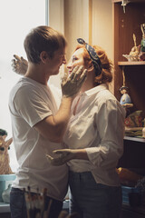 A couple in love in white shirts and jeans, a date in a pottery workshop, working together on one potter's wheel