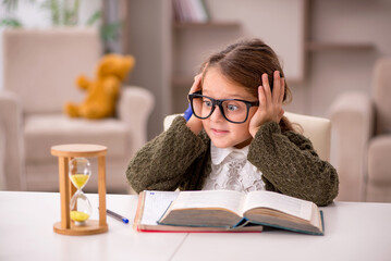 Young little girl studying at home in time management concept