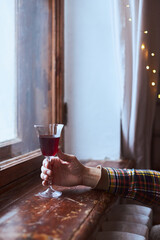 A young man drinks red wine from a vintage glass in an old mansion. Vertical photo.