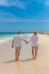Retired couple holding hands walking by the ocean