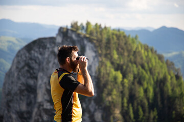 man using binoculars while trekking in nature