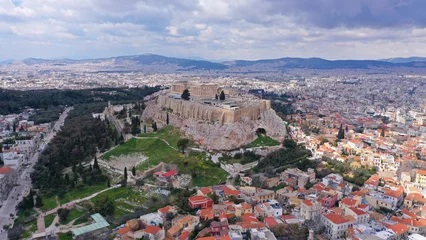 Fotobehang Aerial drone photo of unique Masterpiece of Ancient times the Parthenon on top of iconic Acropolis hill with cloudy sky, Athens, Attica, Greece © aerial-drone