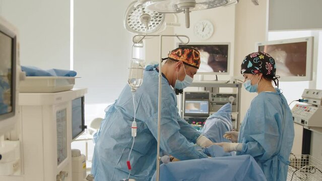 Surgeons team preforming operation in hospital operating theater, male surgeon operating patient,wearing surgical gown,operating room,,working with surgical laparoscopy instruments. Gynecology