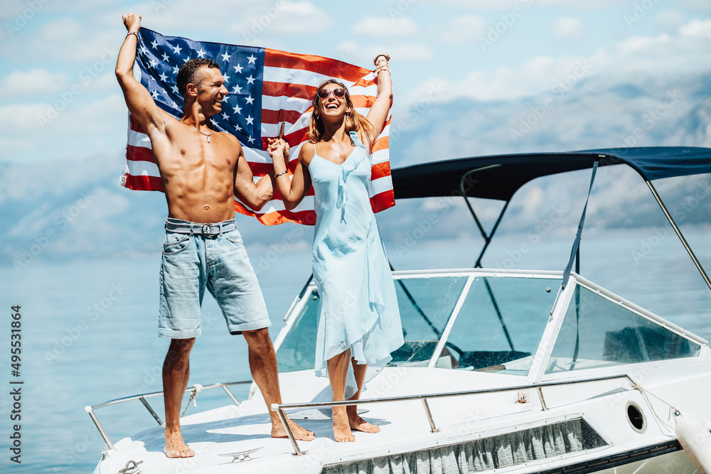 Wall mural Couple With US National Flag Spending Day On Private Yacht