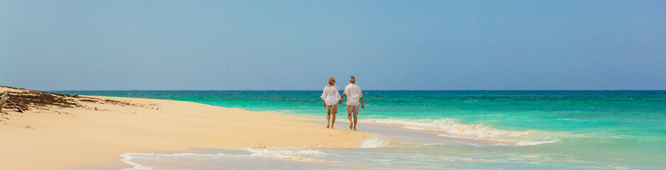 Panoramic view mature couple walking on beach Bahamas