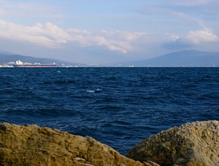 An interesting combination of a stone shore and distant mountains on the horizon of the sea.