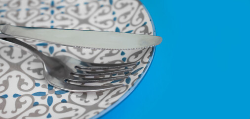 fork, knife, empty plate on a colored background