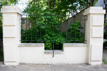Black wrought iron fence between stone pillars
