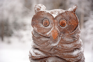 Wooden figurine of a crow covered with owl in the yard of a house