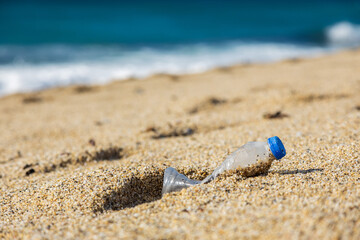 Garbage pollution of the planet. Empty plastic bottle on the beach sand. Consequences of human life