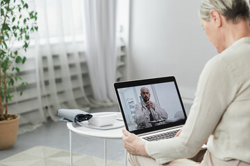 Telemedicine concept, old woman with tablet pc during an online consultation with her doctor in her living room. - obrazy, fototapety, plakaty