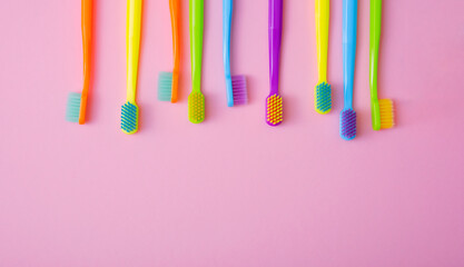 Top view of toothbrushes in colorful on pastel pink background.