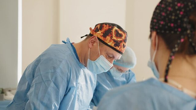 Surgeons team preforming operation in hospital operating theater, male surgeon operating patient,wearing surgical gown,operating room,,working with surgical laparoscopy instruments. Gynecology