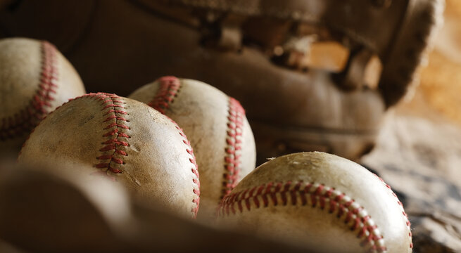 Old baseball equipment close up with balls and blurred background of vintage glove.