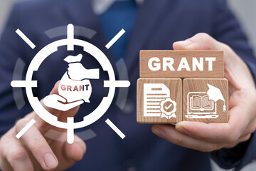 Concept of grants. Application grant. Businessman using virtual touchscreen and holding wooden...