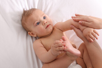 Obraz na płótnie Canvas Mother massaging her cute baby with oil on bed, closeup