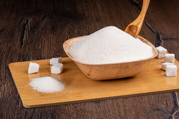 White granulated sugar and lump sugar on a cutting board.