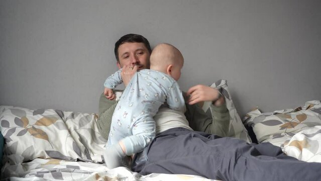 Father with child in the bed. Family and children concept. Happy Young father holds his newborn boy.